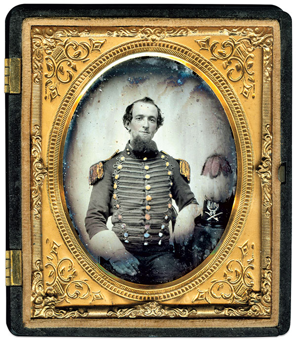 Likely from one of the three cavalry companies attached to the 70th New York State Militia, this trooper wears a blue hussar-style jacket with trefoil chest braid and fringed epaulets. His pattern 1854 cap with tall fountain plume has a militia pattern 1851 Dragoon/Cavalry crossed saber insignia and the brass numeral 70, above which is an example of the shield-shaped Excelsior cap plate prescribed for full dress for non-commissioned officers and enlisted men in the General Regulations for the Military Forces of the State of New-York published in 1858. His leather gauntlets add to his appearance in the mounted service. Sixth plate ambrotype by an unidentified photographer. Author’s collection.