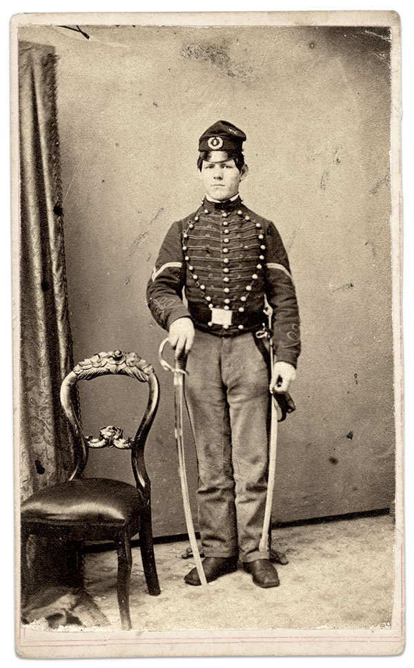 The headgear worn by Cpl. James B. Kevlin of the 3rd has a stiff visor much like a traditional forage cap. He is armed with the Model 1860 cavalry saber issued to and carried by his comrades. Carte de visite by S. Stokes of Trenton, N.J. Rick Carlile Collection.