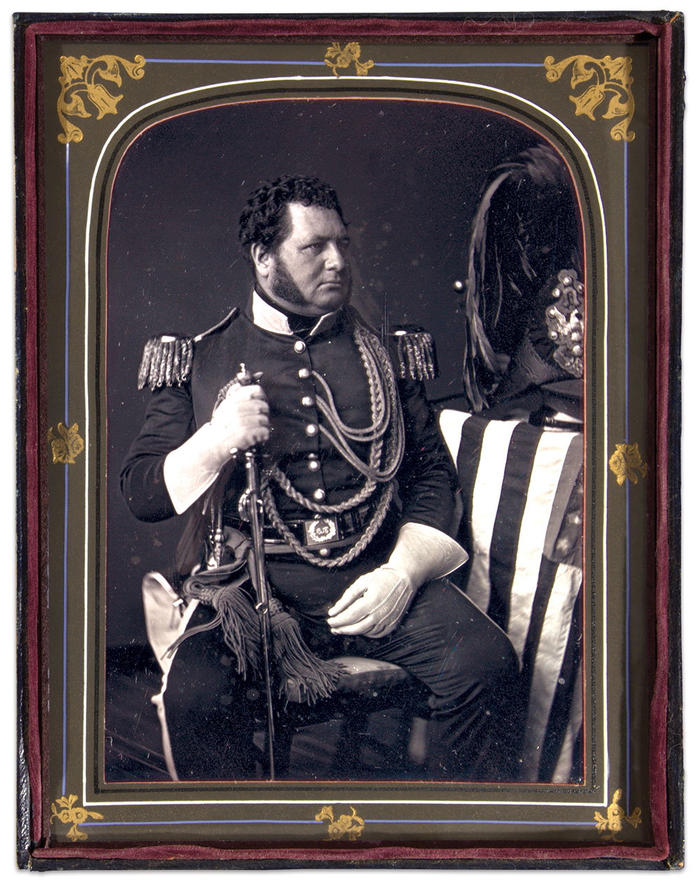 IMPECCABLY ATTIRED: This militia officer ranks as a captain based on the width of his bullion epaulets and single-breasted coat, a variation of the 1847 dress coatee. The twisted gold cord aiguillette fastened under his epaulet strap and draped across his chest indicate he is an aide-de-camp, as does the plumed chapeau on the table (note the Type 2 Pattern 1839 forage cap beside the chapeau). The trim on his collar (and cuffs hidden from view by his gauntlets) and welts on his trouser seams might indicate infantry. The waist belt plate appears to be the 1832 pattern US style. The shine of the belt suggests patent leather, and the two stripes that run the length of the belt are unusual. Also atypical is his sword and scabbard, which appear to have elements of the 1834 general officer and 1840 foot officer models. —Mike Cunningham, Ron Field and Ron Maness. Full-plate daguerreotype by Marcus A. Root of Philadelphia, Pa. Author’s collection.